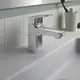 Waschtischarmatur in verchromtem Finish von Ideal Standard. Befestigt an einem weißen Waschbecken mit flacher Oberfläche und vor gefliester Wand.